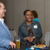 three people laugh around a cocktail round table at celebration event